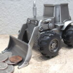 pewter front loader tractor bank that is engravable and picking up coins